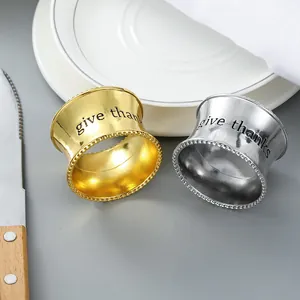 Detalle de servilleteros de metal con grabado give thanks sobre un plato blanco