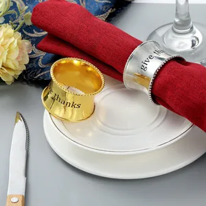 Detalle de servilletero metálico con grabado give thanks y borde de cuentas