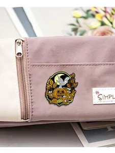 Dettaglio della spilla smaltata di Halloween con zucca e uccello su borsa viola