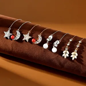 Dettaglio di eleganti orecchini a pendente in oro e argento con perle e strass lucidi