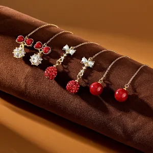 Dettaglio di orecchini a catena dorata con cuori smaltati rossi e pendenti in zircone