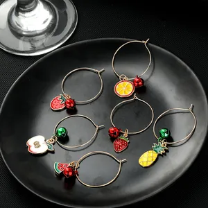 Close-up of six colorful fruit-themed wine glass charms in a black ceramic tray