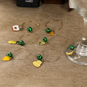 Set of 6 colorful enamel fruit wine glass charms with small green bells on burlap