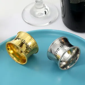 Primer plano de servilleteros de oro y plata con grabado give thanks y bordes de cuentas