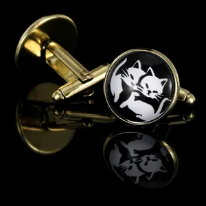 Macro view of gold round cufflinks with cat silhouettes on a reflective black surface