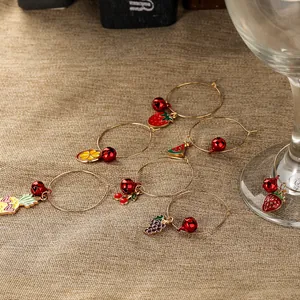 Detailed view of colorful fruit wine glass charms with red bells on brown linen