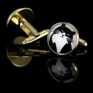 Macro view of round gold-tone cufflinks featuring a cute black and white cat pattern