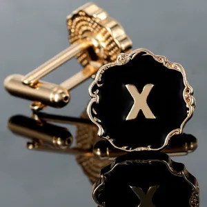 Detail of gold cufflinks featuring a black enamel surface and a metallic letter X design