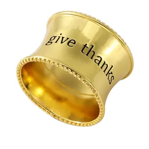 Servilletero dorado con borde perlado y grabado 'give thanks' sobre fondo blanco