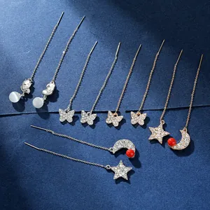 Dettaglio di orecchini a catena con farfalle in oro e argento, zirconi e perle preziose