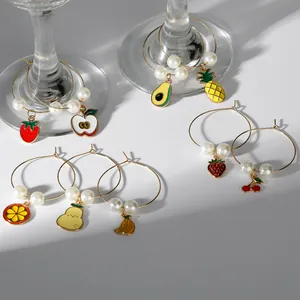 Detail view of fruit-themed wine glass rings with pearls on elegant stemware