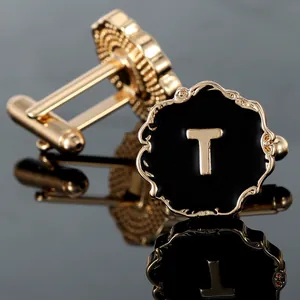 Macro detail of luxury men's cufflink featuring gold letter T on black enamel finish
