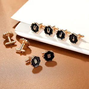 Detailed view of round gold cufflinks with black enamel and gold alphabet initials