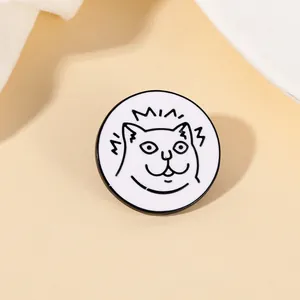 Macro detail of round white enamel pin featuring a cute black and white cartoon cat face