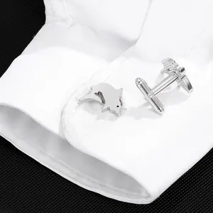 Boutons de manchette dauphin en argent élégants présentés sur un poignet de chemise