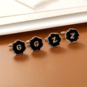 Detailed close-up of gold and black enamel cufflinks with letters G and Z on leather surface