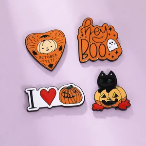 Close-up of four Halloween enamel pins featuring ghosts, pumpkins, and a black cat