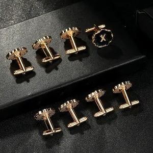 Men's gold cufflinks with black enamel circle and gold letter X on a dark background
