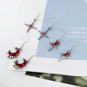 Detail of silver drop earrings with red crystal moons and stars on a white card