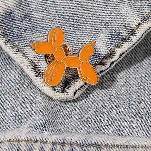 Spilla in smalto a forma di cane palloncino arancione su tessuto denim blu e bordi dorati