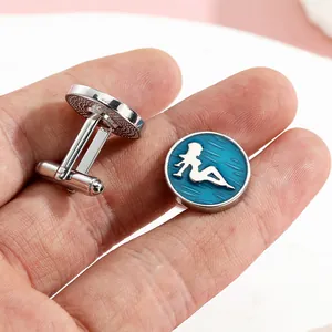 Close-up of silver round cufflinks with blue enamel and female silhouette inlay