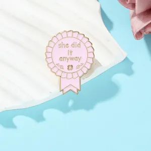 Detail of pink enamel badge with gold trim and motivational she did it anyway lettering