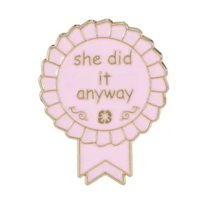 Pink rosette enamel pin with golden metal outline and she did it anyway text