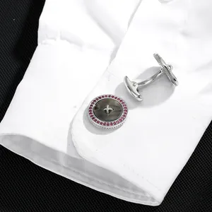 Silver round button cufflinks with black shell and pink stones on a white shirt