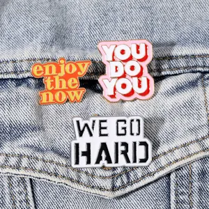 Set di tre spille in smalto con slogan motivazionali su sfondo in tessuto denim blu