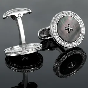 Macro view of silver round cufflinks with black shell inlay and pavé zircon border