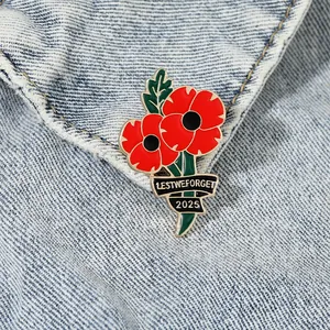 Poppy flower enamel brooch with 2025 Lest We Forget ribbon pinned on blue denim jacket