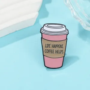 Macro shot of pink enamel coffee cup brooch with 'LIFE HAPPENS COFFEE HELPS' text