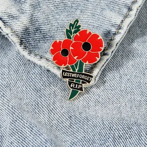 Macro detail of red poppy enamel pin badge with Lest We Forget text on denim fabric