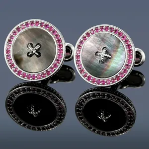 Macro detail of luxury round cufflinks with grey shell, cross stitch, and purple gemstones