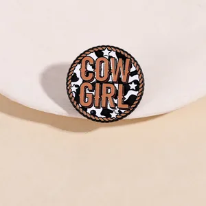 Détail macro de la broche en émail Cowboy avec texte Cow Girl et motifs de vache