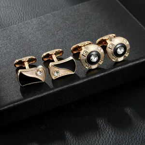 Detailed close-up of gold cufflinks with black enamel and inset crystals on a dark box