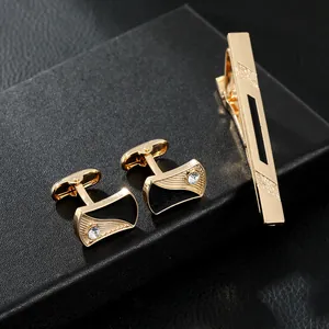 Close-up of gold and black cufflinks and tie clip set with wavy enamel and crystals