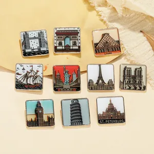 Macro shot of square enamel pins featuring golden landmarks on warm textured fabric
