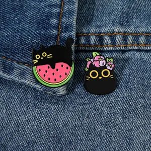 Dettaglio di spillette in smalto a forma di gatto nero su tessuto di jeans
