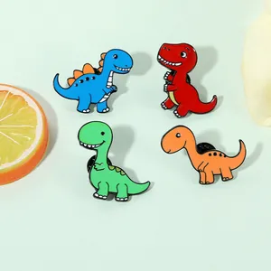 Gros plan de quatre pin's dinosaures colorés en émail sur un fond vert pastel