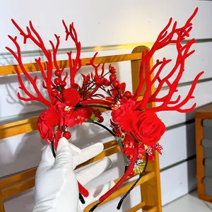 Close-up of Christmas reindeer headband with red antlers, faux roses and festive berries