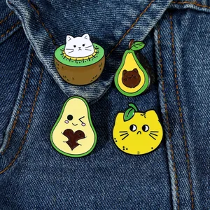Detail of four cute fruit-shaped cat enamel pins pinned on a dark blue denim jacket