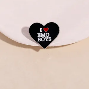 Macro detail of black heart enamel pin with I Heart Emo Boys text and silver metal edges