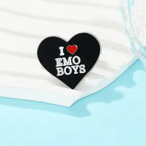 Close-up of heart enamel pin with I Emo Boys text on white wavy display stand