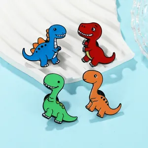 Détail de quatre broches dinosaures colorées en émail bleu, rouge, vert et orange exposées
