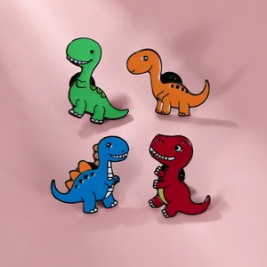 Détails de quatre pin's en émail colorés en forme de dinosaures sur fond rose doux
