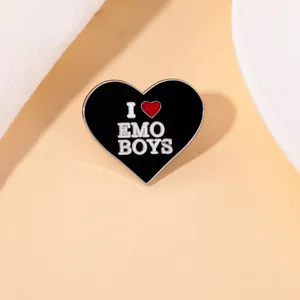 Detail shot of a black heart enamel brooch featuring white I Love EMO BOYS text