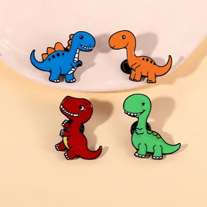Détail de quatre épingles dinosaures colorées en émail sur un plateau en céramique décoré