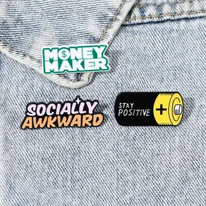 Three enamel pins set featuring Socially Awkward and Stay Positive battery design on denim