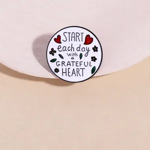 Détail macro de la broche ronde en émail avec message Grateful Heart sur plateau